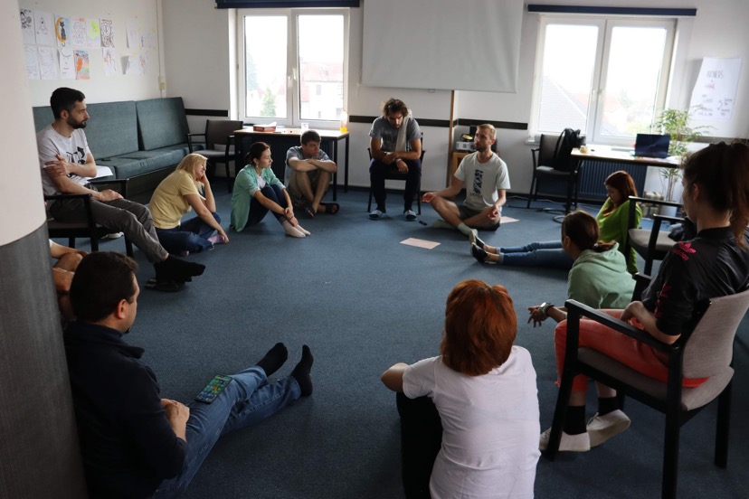 Grupa ludzi na szkoleniu, siedząca na podłodze