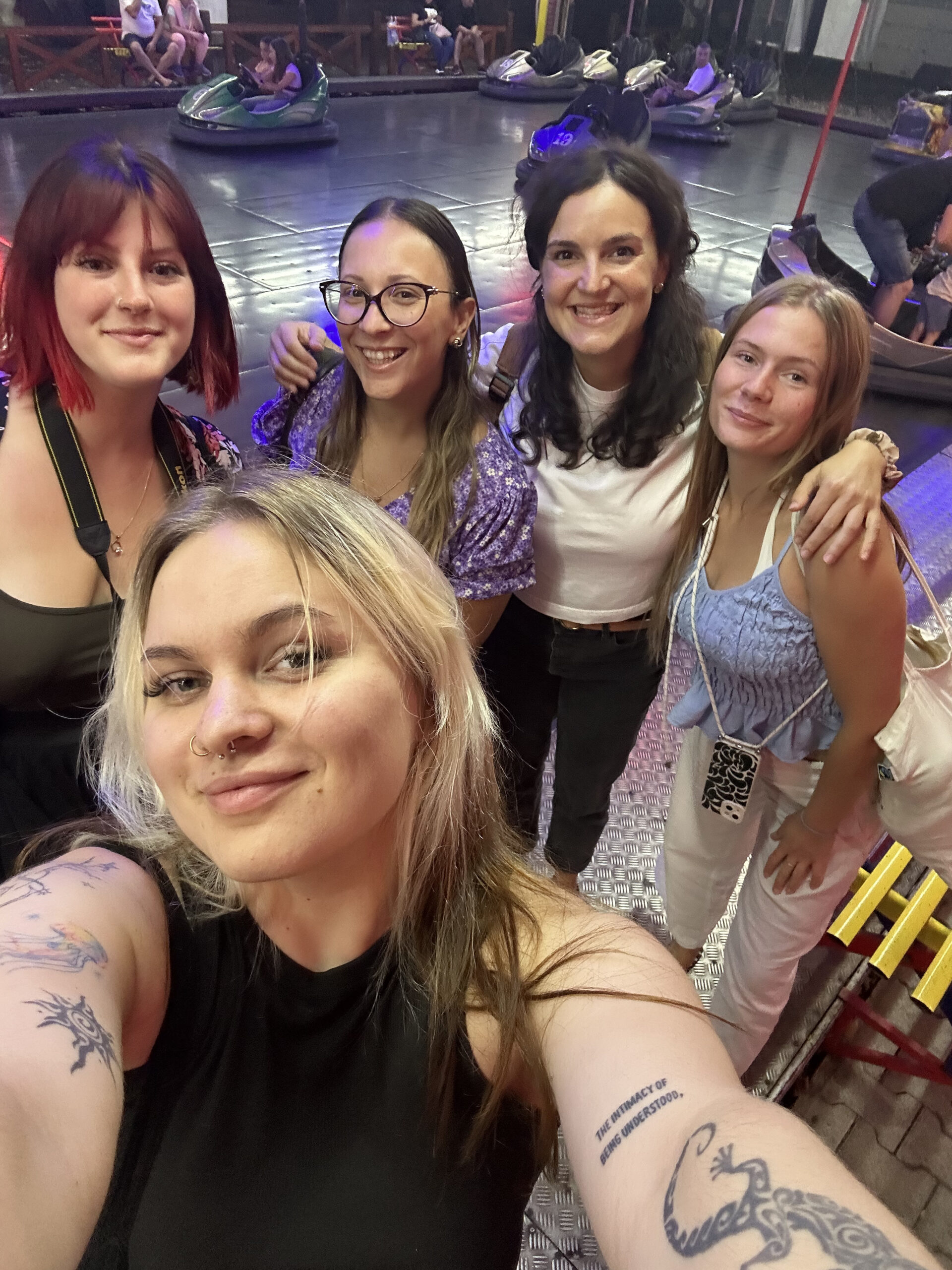 ARTiculate3 Pięć uśmiechniętych uczestniczek, robiących sobie selfie w wesołym miasteczku.